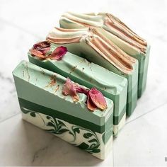 three soap bars with flowers on them sitting next to each other in front of a marble counter top