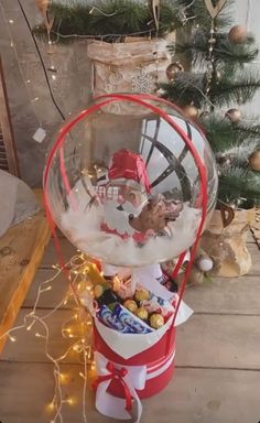 a santa clause in a snow globe filled with chocolates and candies next to a christmas tree