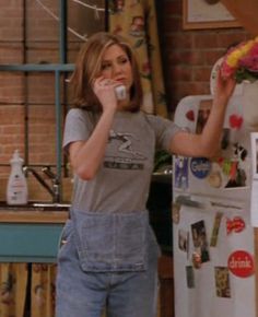 a woman standing in front of a refrigerator talking on a cell phone