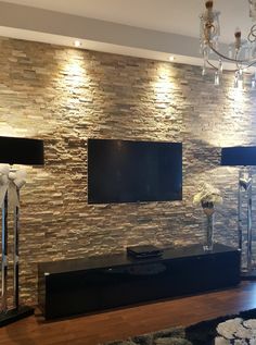 a living room with stone wall and chandelier