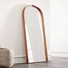 a large mirror sitting on top of a wooden floor next to a basket and chair