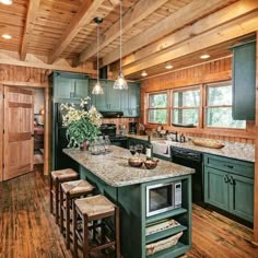 a kitchen with green cabinets and an island in the middle, surrounded by stools