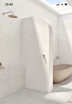 a white bathroom with an oval bathtub next to a sink and shower faucet