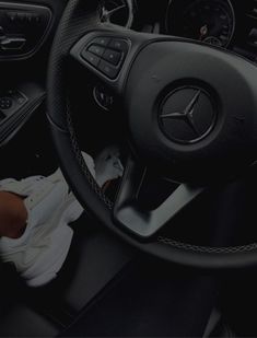 the interior of a mercedes car with black leather steering wheel cover and white sneakers on the floor