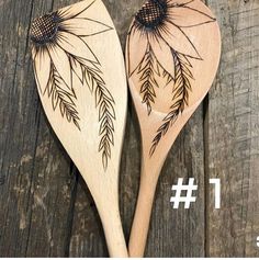 two wooden spoons with designs on them sitting on a table next to each other