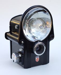 an old style projector lamp on a white background with the lens slightly open and it's head turned upside down