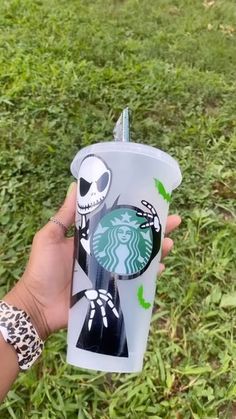 someone holding up a starbucks cup with a skeleton on it and a spider in the cup