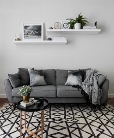 a living room with grey couches and black and white rugs on the floor