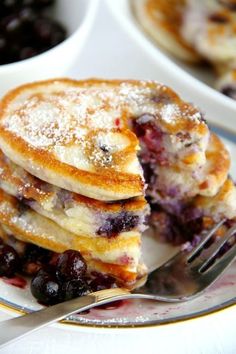 pancakes with blueberries and powdered sugar are stacked on top of each other, ready to be eaten