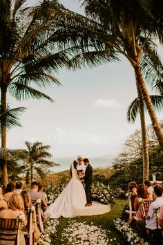 a bride and groom standing at the end of their wedding ceremony in front of palm trees