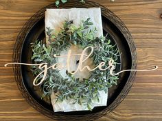 a black plate with a white napkin and some greenery on it that says gather