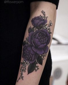 a woman's arm with purple flowers and leaves on the left side of her arm