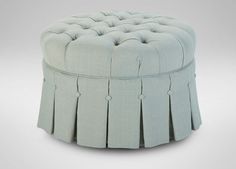 a round ottoman with pleated skirting on the front and back sides, in light blue