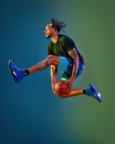 a man with dreadlocks is jumping in the air holding a basketball and wearing blue shoes