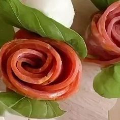 some food that is laying on top of a wooden table next to leaves and flowers