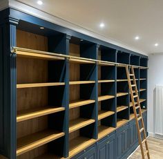 an empty room with blue bookcases and ladder