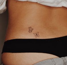 a woman's stomach with two small butterflies on the side, tattooing it