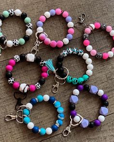 several bracelets with different colored beads and skulls on them sitting on a wooden surface