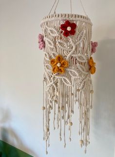 a crocheted mobile with flowers hanging from it's sides on a wall