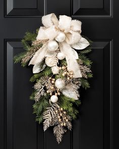 a christmas wreath on the front door with white balls and greenery hanging from it