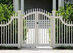 an open white gate in front of a house