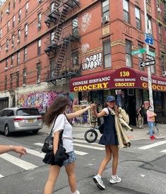 two girls crossing the street in front of a building