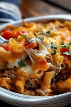 a close up of a plate of pasta with meat and cheese on it, with a spoon in the bowl