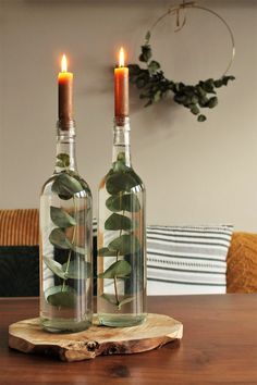 two wine bottles with plants in them sitting on a wooden table next to each other