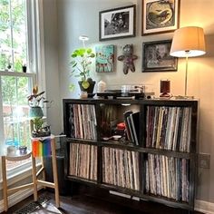 an old record player is sitting in front of a window with pictures on the wall