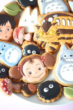 an assortment of decorated cookies on a white plate with cartoon characters and children's faces