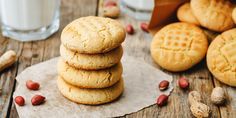 a stack of cookies sitting on top of a wooden table next to a glass of milk