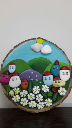 a painted wooden slice with flowers and houses on it