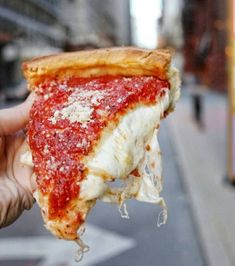 a slice of pizza is being held up to the camera