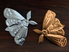 two metal butterflies sitting on top of a wooden table