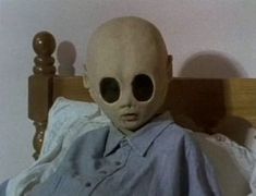 an alien head sitting on top of a bed