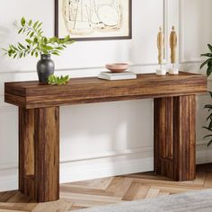 a wooden table with two vases on top of it in front of a wall