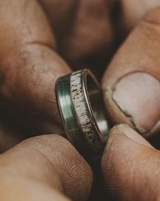 two hands holding a wedding ring that has been made from antelope and silver