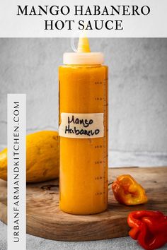 mango habanero hot sauce in a glass bottle on a cutting board with peppers