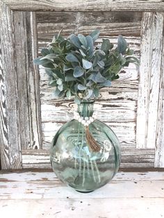 a vase with some flowers in it sitting on a shelf next to a wooden wall