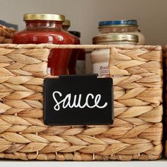 a basket with some food in it on top of a counter next to jars and sauces