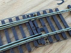 an old train track laying on top of a wooden floor next to a wrench