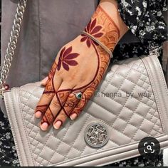 a woman's hand with henna tattoos on it and a purse behind her