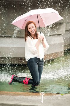 a woman holding an umbrella while standing in the water with her feet on the ground