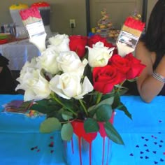 a vase filled with white and red roses on top of a blue cloth covered table