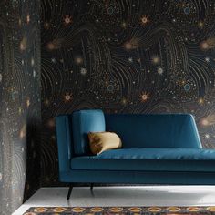 a blue couch sitting in front of a wall with stars and swirls on it