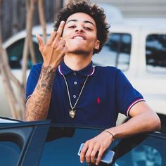 a young man with tattoos on his arm leaning out of a car window and talking on the phone