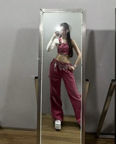 a woman taking a selfie in front of a mirror wearing pink pants and crop top