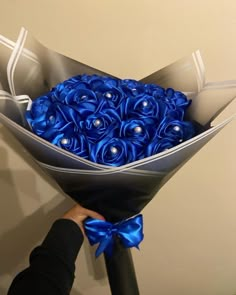 a bouquet of blue roses is being held by a woman's hand with a ribbon around it