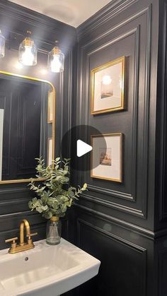 a white sink sitting under a bathroom mirror next to a gold faucet and framed pictures