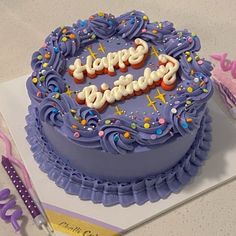 a purple birthday cake with candles and decorations on the top is sitting on a table